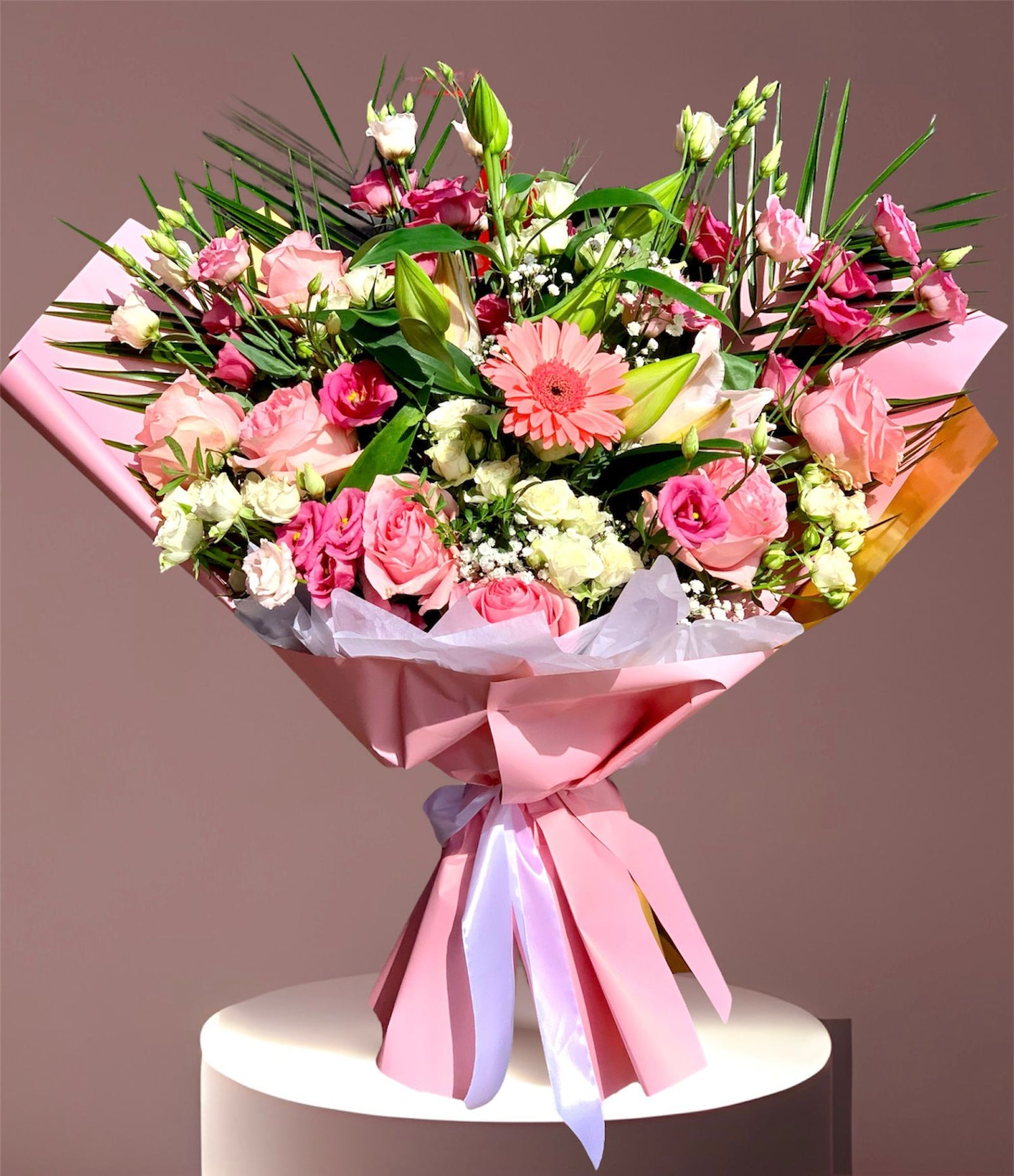 Buchet elegant de flori roz și albe, cu ambalaj roz și fundă.